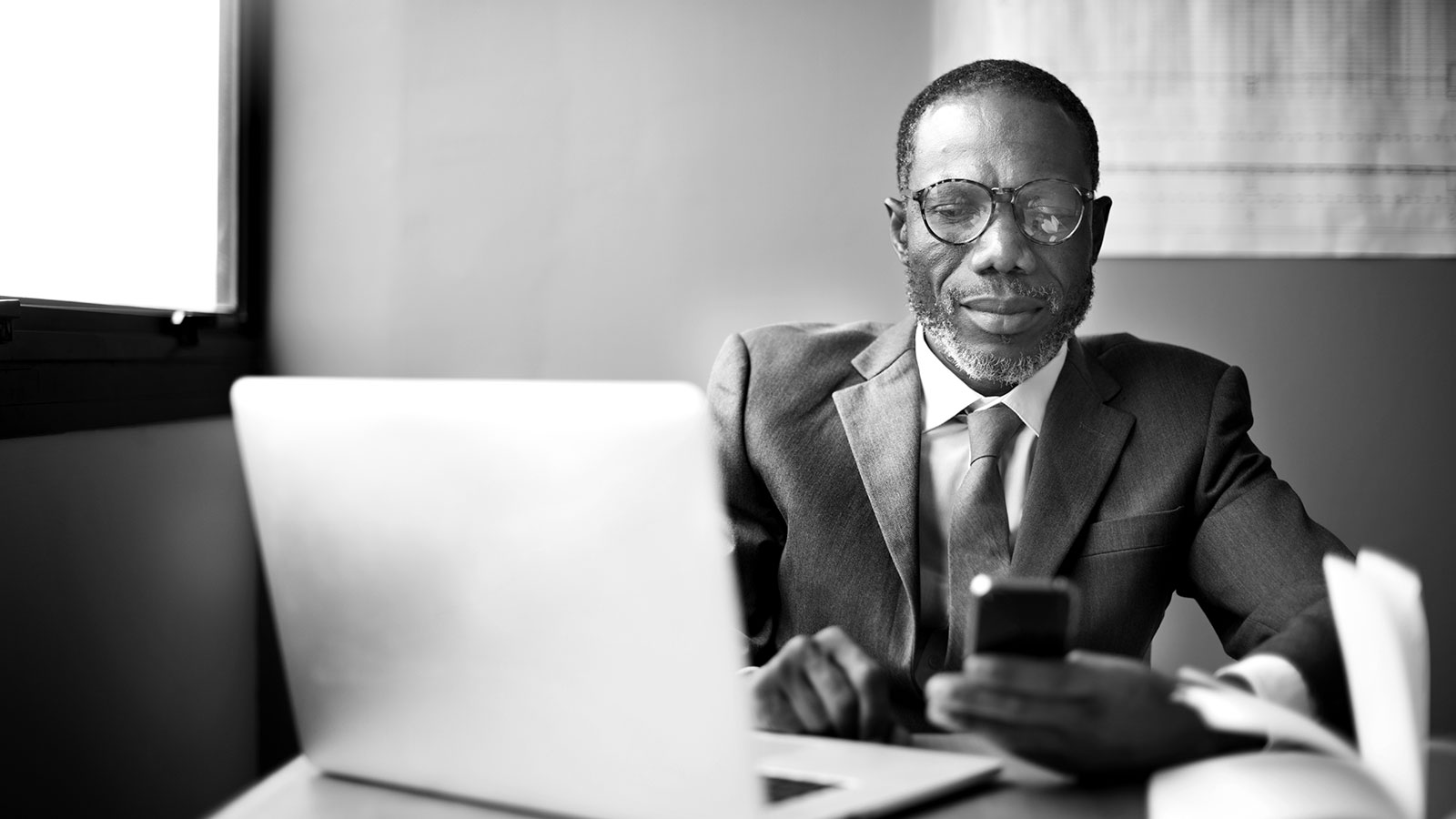 LeasePilot Brand Identity – Photography: Middle-Aged Businessman Using Smartphone and Laptop in Black & White